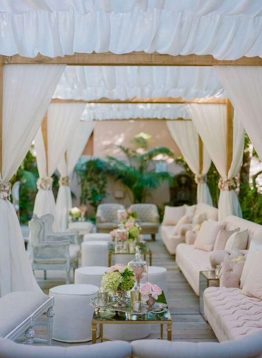Zona chill out con sofás bajo estructura de telas en boda